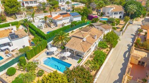 Ein Wohngebiet mit einem großen Haus, das einen Pool, Solaranlagen und einen gepflegten Garten hat.