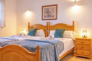 A double bed with a wooden headboard, two bedside tables, a wall-mounted painting, and a lamp on each side.