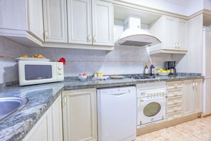 A kitchen with white cabinets, a microwave, a dishwasher, and a stove.