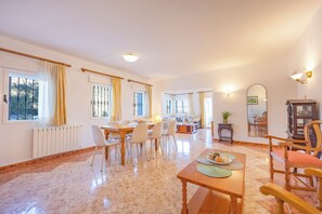 A spacious living area with a dining table, chairs, and a seating area with a sofa and armchairs.
