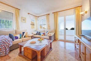 A spacious living area with a sofa set, a coffee table, and a television.