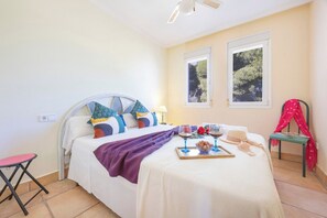 A bedroom with a bed, a bedside table, a chair, and a window. - Villa Ursula - Plusholidays (Calpe)