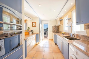 A modern kitchen with granite countertops, built-in appliances, and a view to the outside. - Villa Ursula - Plusholidays (Calpe)