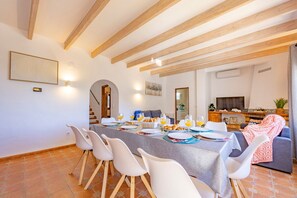 A dining area with a long table, chairs, and a sofa.