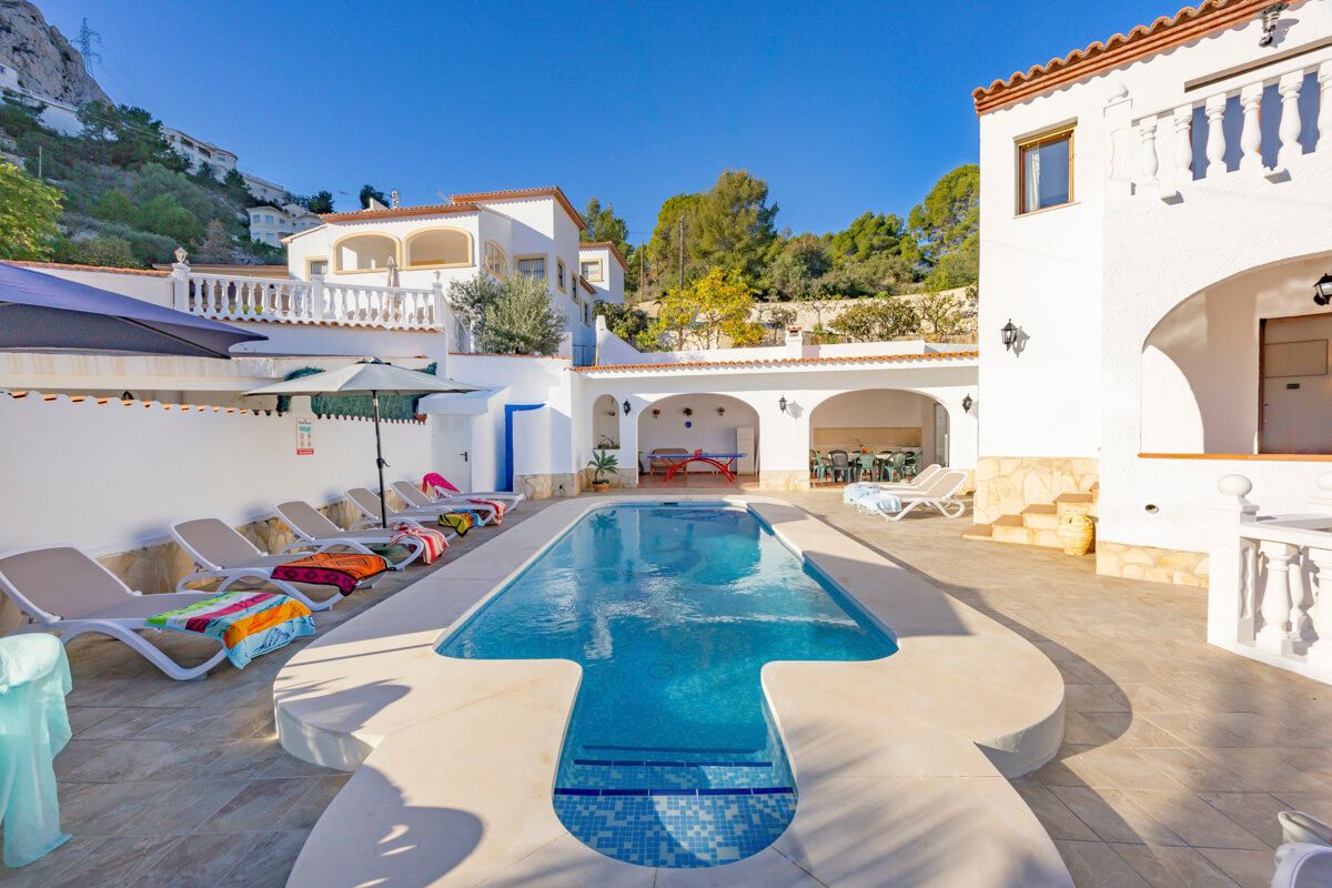 A pool area with lounge chairs and a clear blue pool.