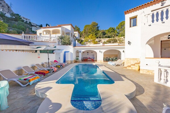 A pool area with lounge chairs and a clear blue pool.
