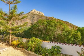 A mountainous landscape with a white wall and a garden in the foreground.