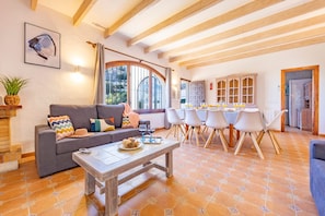 A cozy living room with a sofa, coffee table, and dining area with chairs and a table.