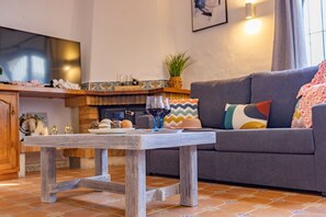 A living room with a grey sofa, a wooden coffee table, and a television on the wall.