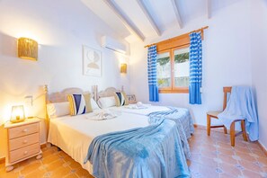 A double room with two beds, a nightstand, a chair, and a window with curtains.