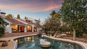 Una casa circondata da alberi, con piscina e patio.