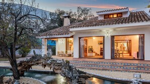 Una casa moderna con piscina, ponte in pietra e zona relax all'aperto.