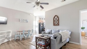A modern living room with a grey sofa, a wooden coffee table, and a ceiling fan.