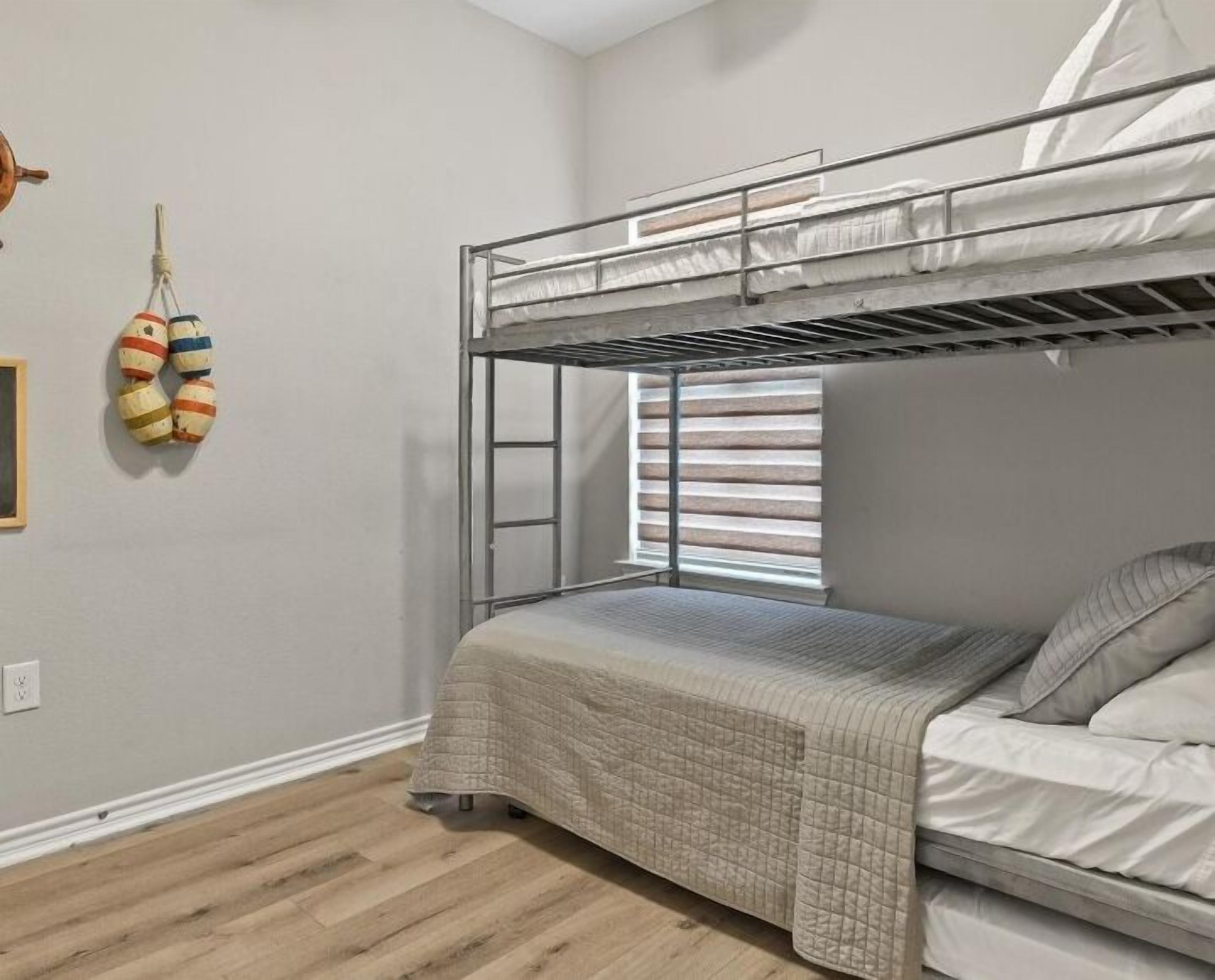 A bunk bed room with a window, a wall-mounted toy, and a wooden floor.