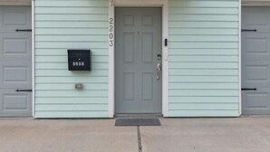 A building with a light green exterior, a grey door, and a mailbox on the left.