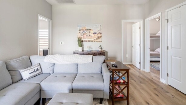 A modern living room with a grey sectional sofa, a small table, and a painting on the wall.