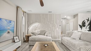 A modern living room with a sofa, a coffee table, and a TV on a white wall. - Royal Retreat: All Inclusive Champions Gate Resort 6BD6BA Free Heated Pool Villa (Four Corners)