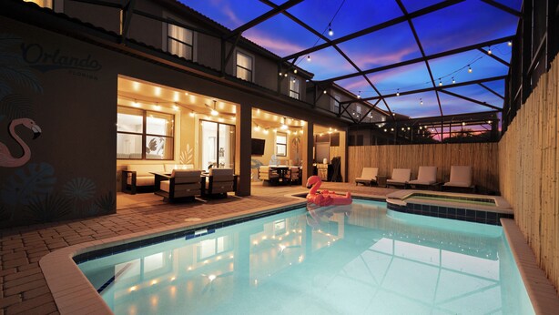 A swimming pool with a glass ceiling, lounge chairs, and a flamingo float. - Royal Retreat: All Inclusive Champions Gate Resort 6BD6BA Free Heated Pool Villa (Four Corners)