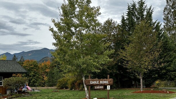 Placa de madeira para as Cabins Eagle Ridge, com vista para montanhas ao fundo.