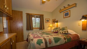 Een slaapkamer met een groot bed, houten meubels, een raam met gordijnen en wandlampen.