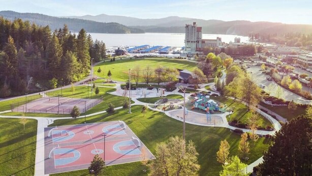 A sports complex with basketball courts, a playground, and a large building in the background. - Dwntwn CDA Historic Remodel - Walk to Lake with Hot Tub! (Coeur d'Alene)