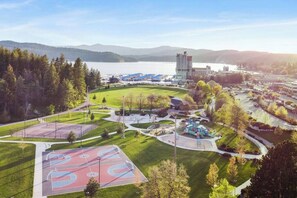 Un complexe sportif comprenant des terrains de basketball, une aire de jeux et un grand bâtiment en arrière-plan.