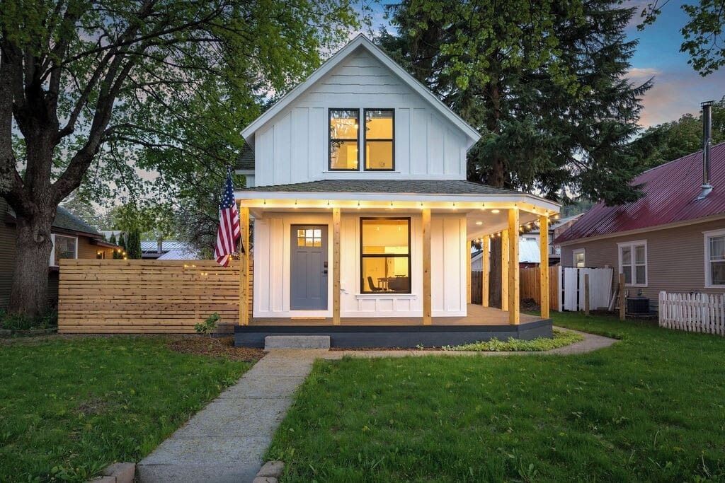 A two-story house with a covered porch, a flag, and a well-maintained lawn.