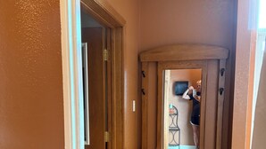 Un pasillo con un banco de madera, una puerta y un ventanal.