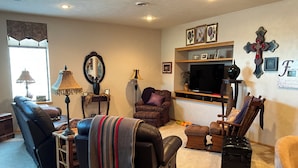 A living room with a sofa, armchair, and a television on a stand.