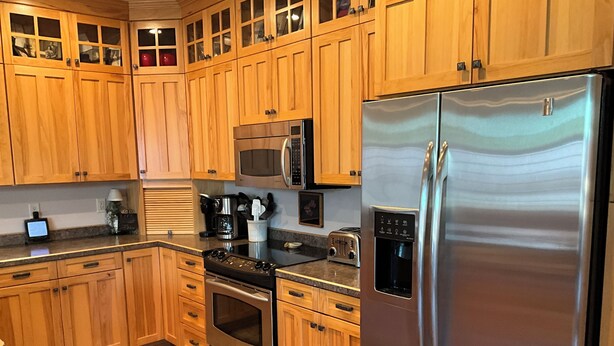 Una cocina moderna con armarios de madera, electrodomésticos de acero inoxidable y encimera negra.