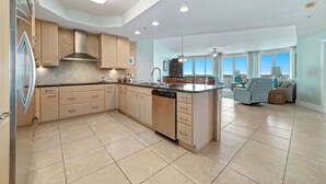 Una cocina moderna con una isla central, electrodomésticos integrados y un amplio ventanal con vistas al salón.