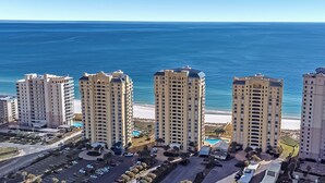 A high-rise hotel with multiple floors, a parking area, and a view of the ocean.