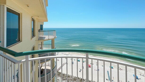 A balcony with a view of the beach and ocean.