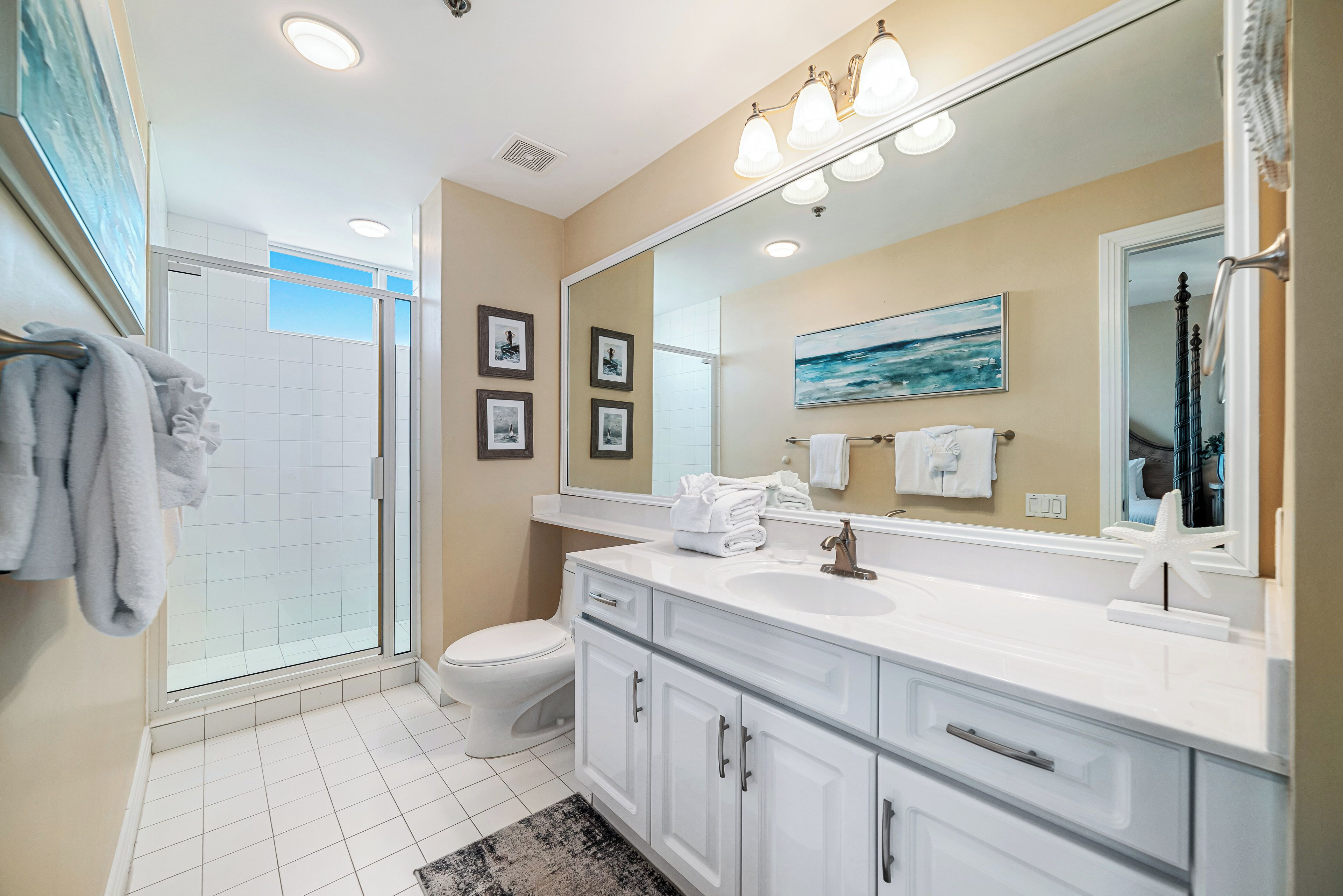 A modern bathroom with a glass shower enclosure, white vanity, and a large mirror.