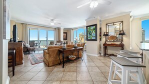 A spacious living room with a large window, a ceiling fan, and a dining area with a table and chairs.