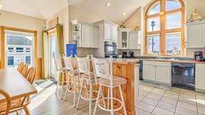 A modern kitchen with white cabinets, a wooden island, and bar stools.