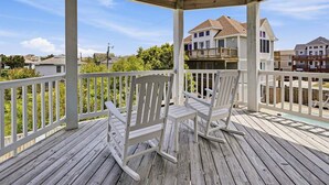 A wooden deck with white railings and two rocking chairs.