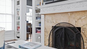A room with a fireplace, a bookshelf, and a table with a magazine. - Charming 3-bedroom house with WiFi, AC in welcoming Lake Worth Beach (Lake Worth Beach)