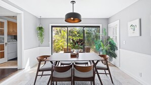 A dining area with a table, chairs, and a hanging plant. - Charming 3-bedroom house with WiFi, AC in welcoming Lake Worth Beach (Lake Worth Beach)
