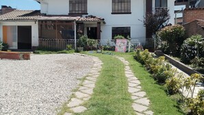 Una casa de dues plantes amb teulada de rajola, un porxo frontal i un camí pavimentat que condueix a l'entrada.