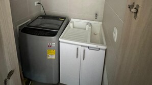 Une petite cuisine équipée comprenant un lave-linge intégré, un petit évier et un étendoir.