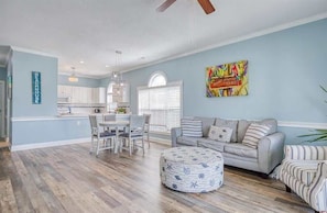 A spacious living area with a dining table, a sofa, and a colorful artwork on the wall.