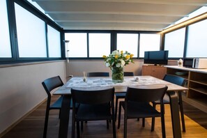 Un comedor con una mesa, sillas, un florero, un televisor y un microondas.