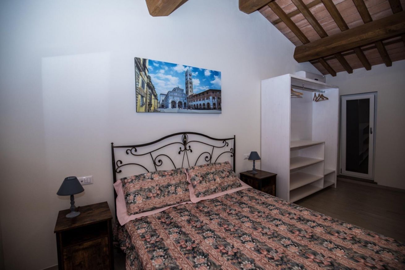 Un dormitorio con cama, mesita de noche, armario y un cuadro en la pared.