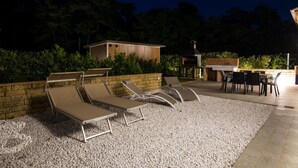 Een terras met loungezetels en een barbecue.