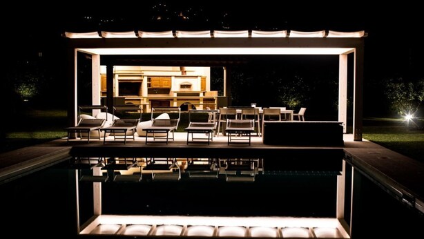 Een buitenzwembad met ligbedden en een pergola.