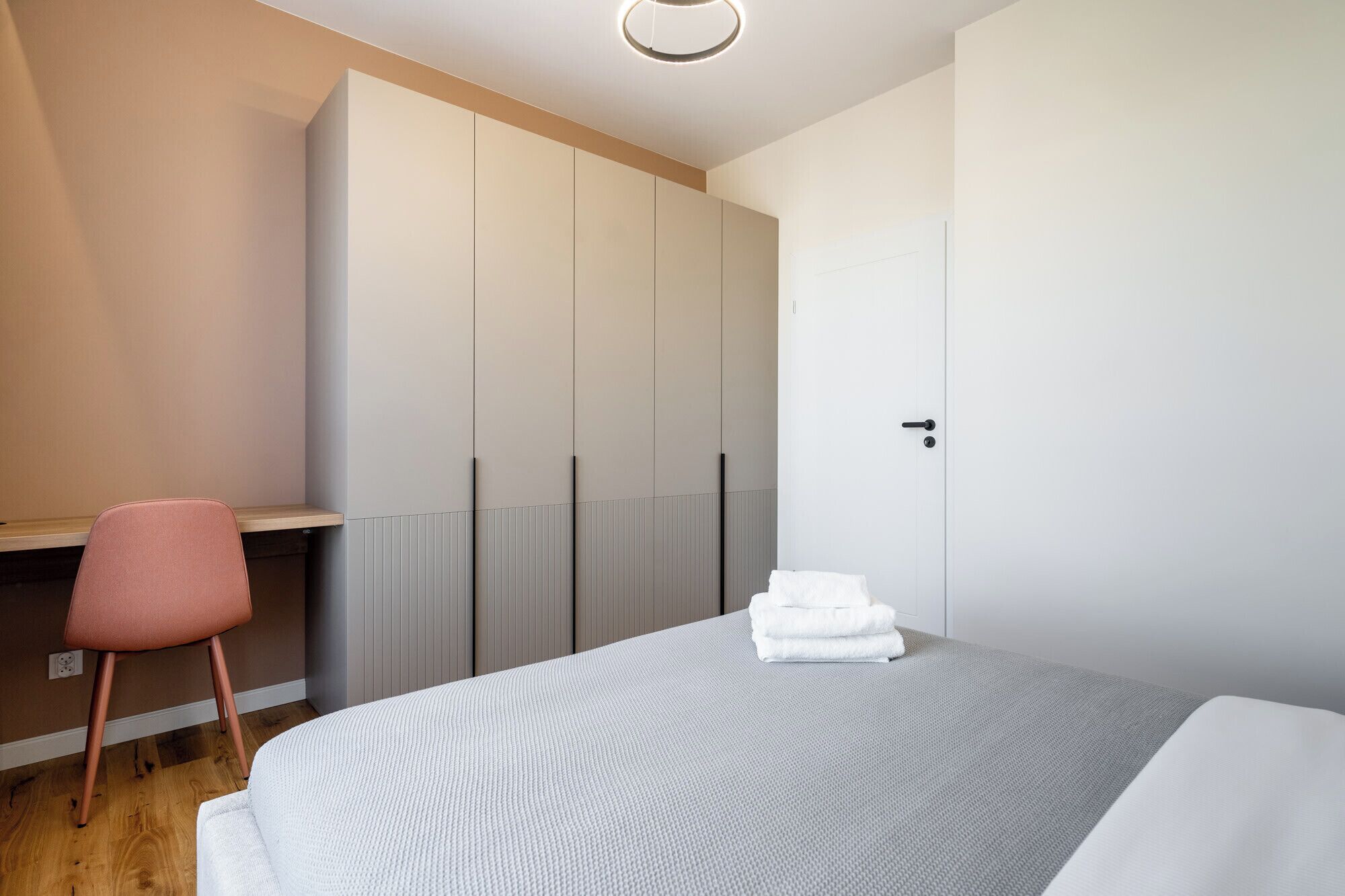A bedroom with a bed, a desk, and a chair.