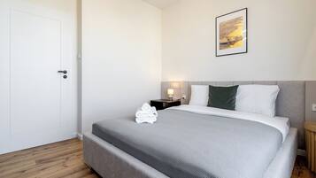 Una habitación de hotel con una cama, una mesita de noche, una lámpara de pared y un cuadro enmarcado.