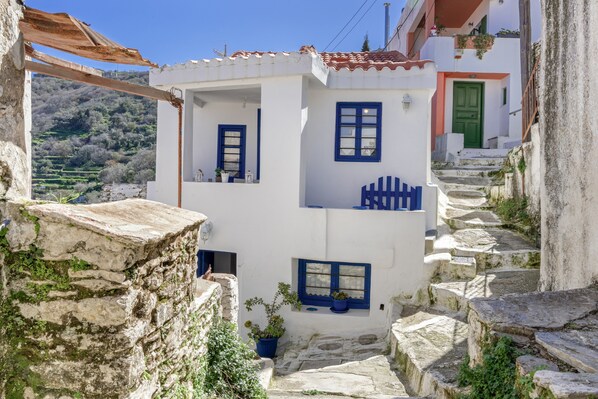 Un edificio blanco con detalles azules, escalones de piedra y una puerta verde.