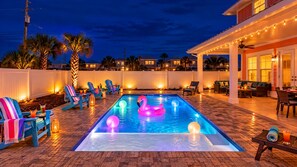 En swimmingpool med oppustelige flamingoer og liggestole.